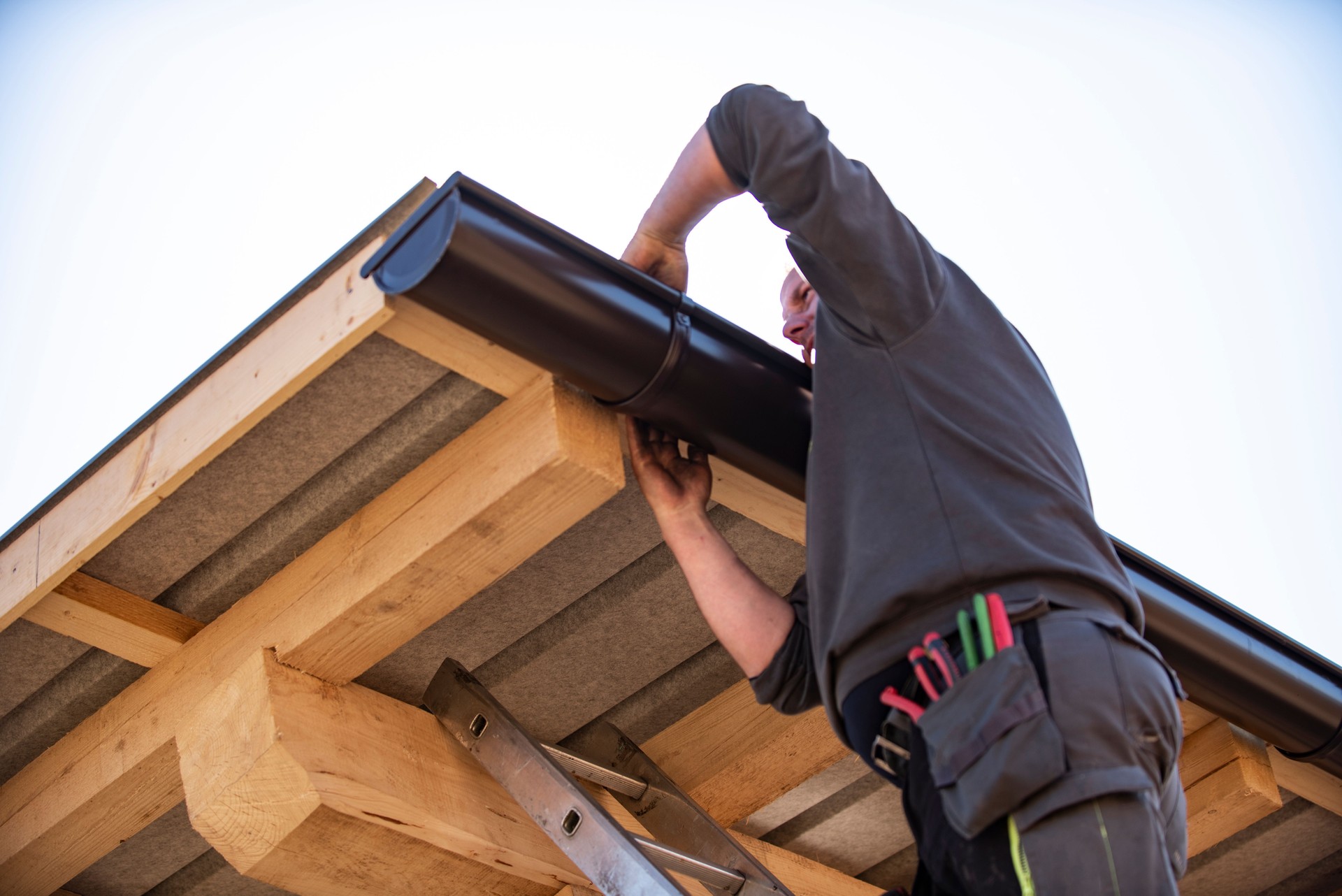 Worker on roof installing gutter